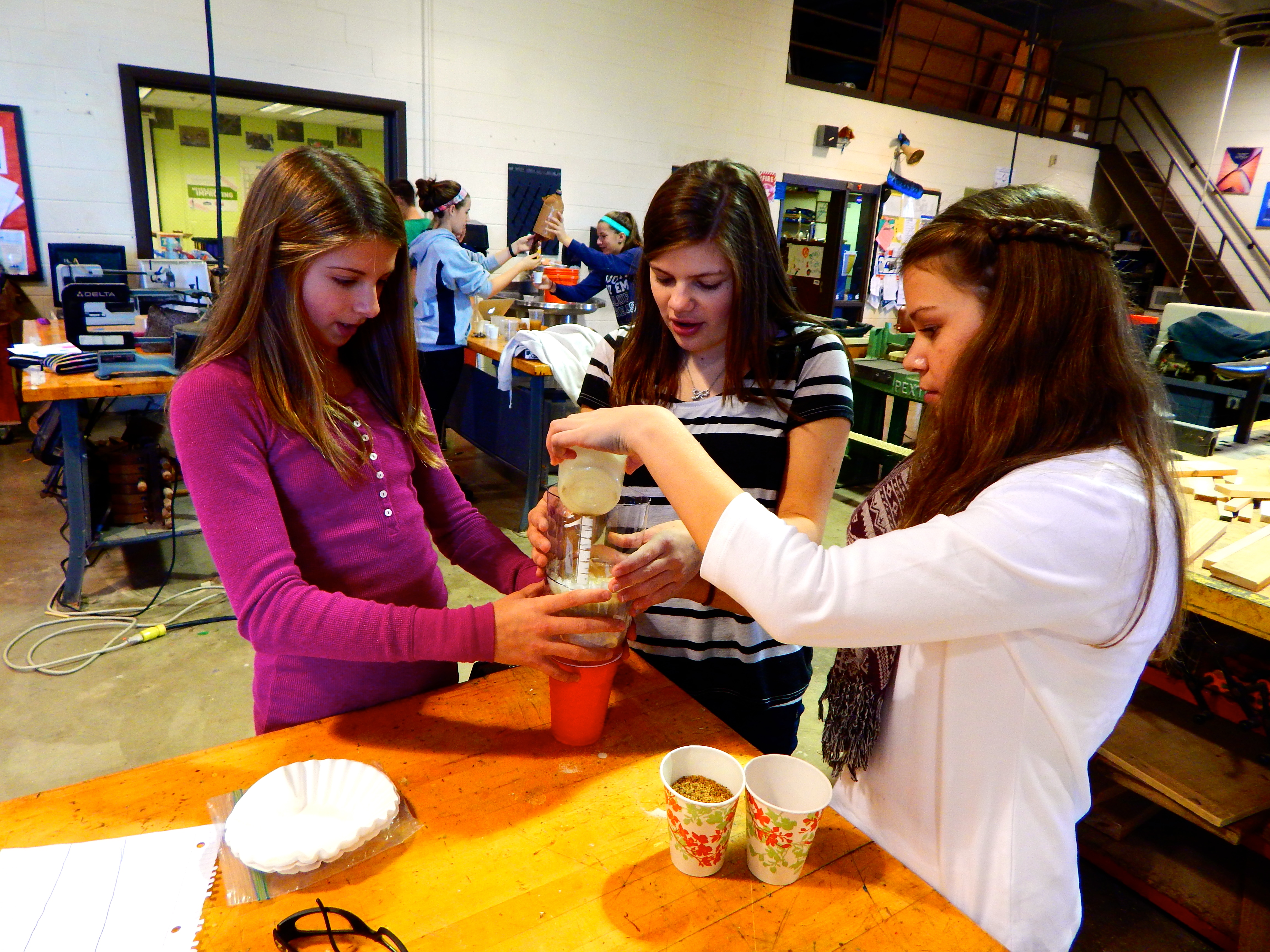 From left to right, Abby, Anna and Christa test their water filter. Lab groups are designing filters for specific assigned countries. They must use items that citizens of that country would have on hand. These girls have been assigned Bangladesh, a country with an abundance of arsenic in its water. They are using brick chips and cigarette ashes in attempt to filter the arsenic.