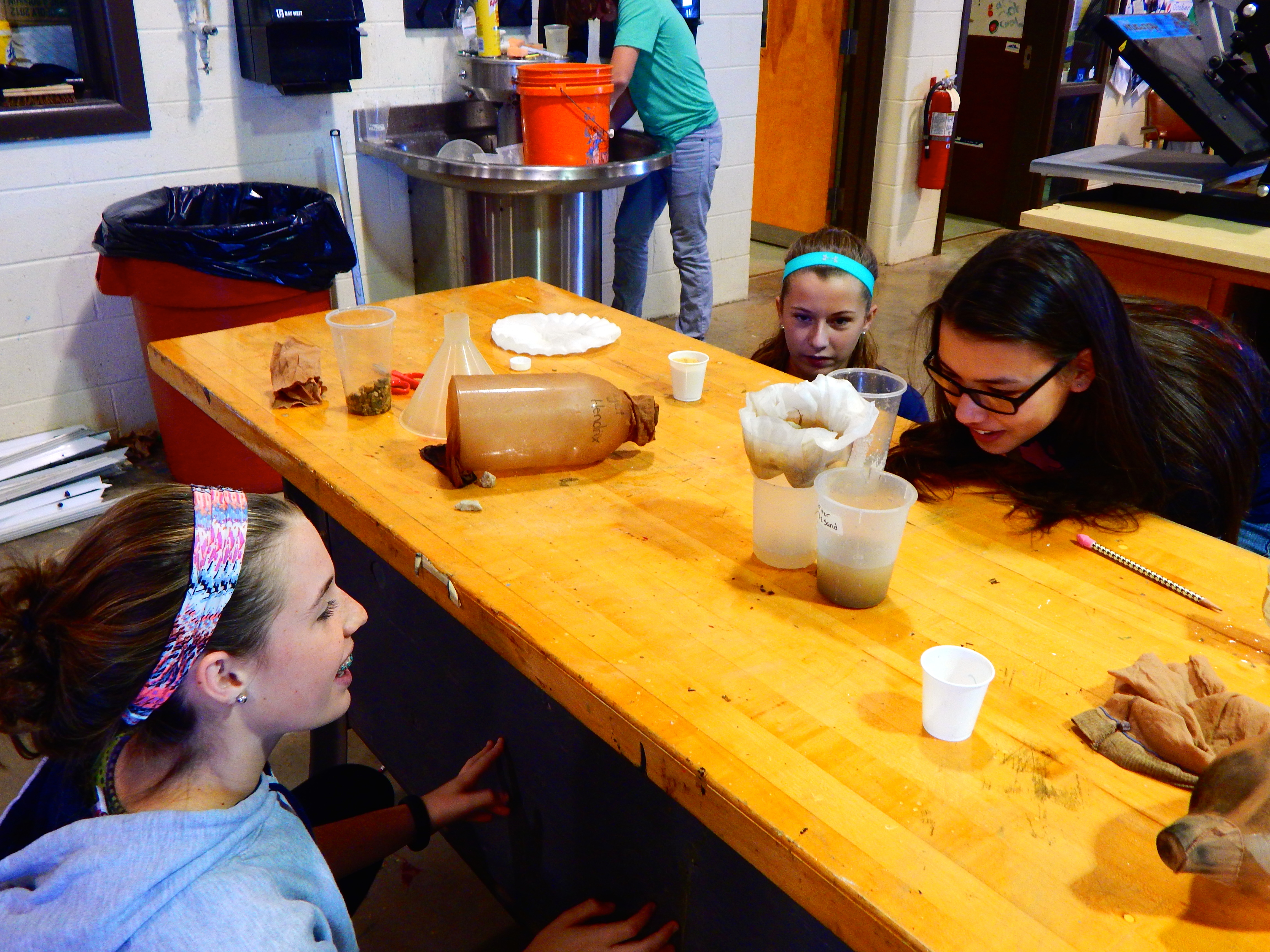 Students closely examine the cleanness of the water they filtered.